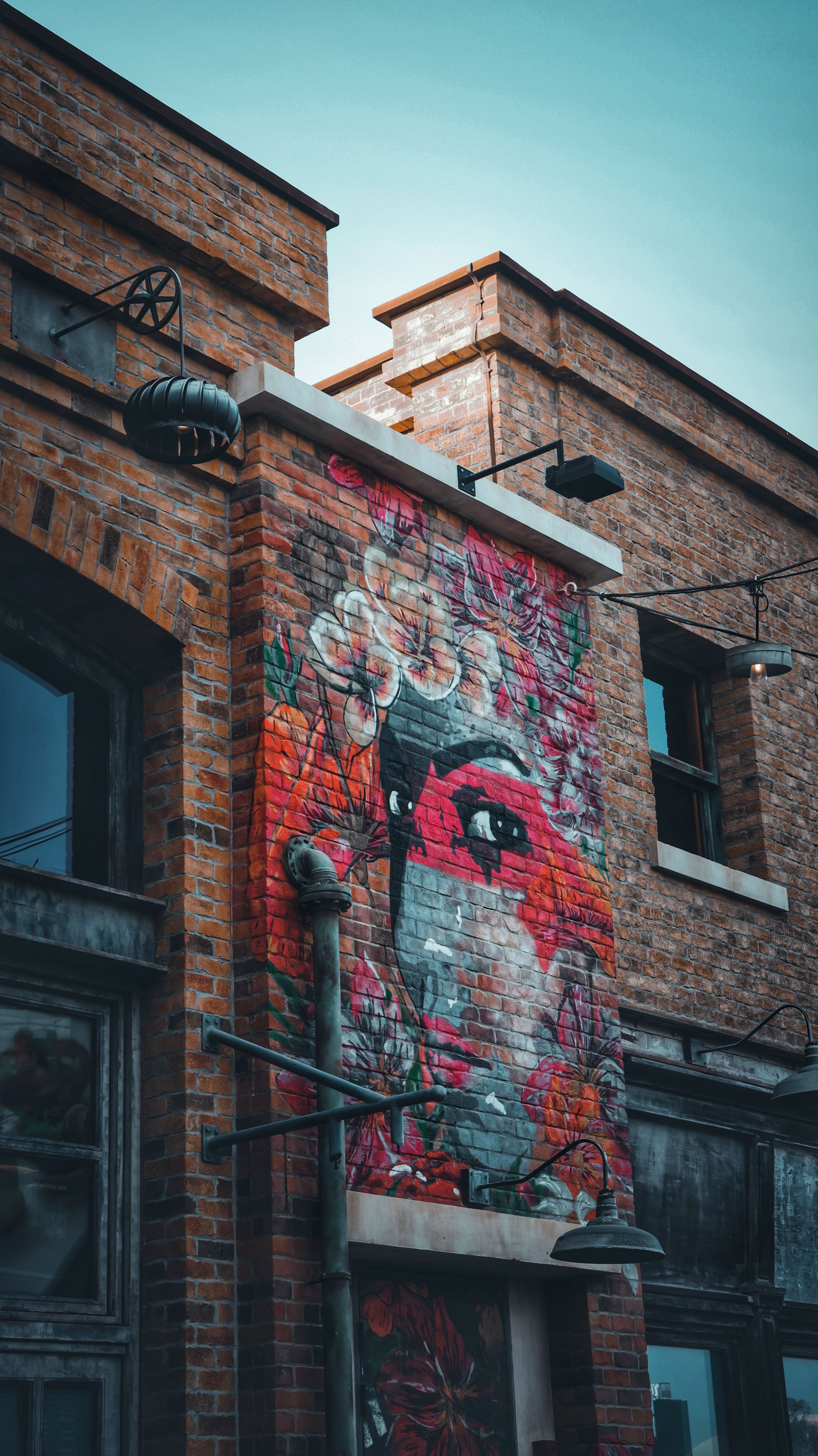 A large street-art mural of a red bird painted on the side of an old brick building